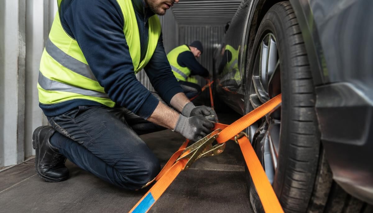 Workers strapping a car's wheels inside a container