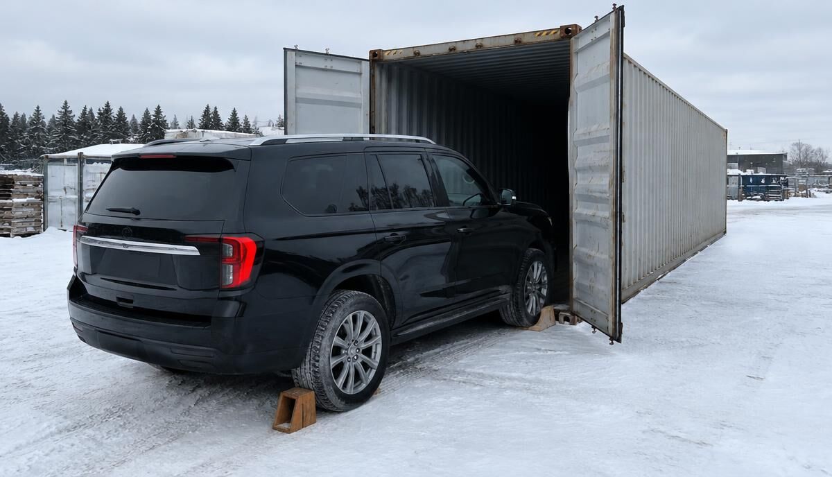 VUS noir prêt à entrer dans un conteneur dans une cour enneigée au Canada